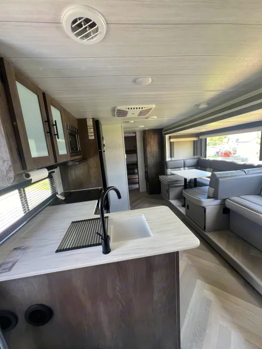 Modern RV rental interior showcasing a kitchen, dining booth, and lounge area. Bright & spacious for travel.. Forest River Salem Cruise Lite 2022
