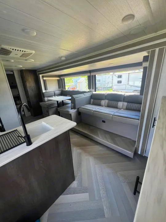 Spacious RV rental interior featuring a modern kitchen, dining area, and large grey sofa for comfortable travel.. Forest River Salem Cruise Lite 2022