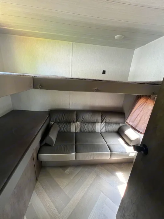 RV rental: Dark grey convertible sofa, upper bunk, and lower bunk/bench. Light walls, herringbone floor.. Forest River Salem Cruise Lite 2022
