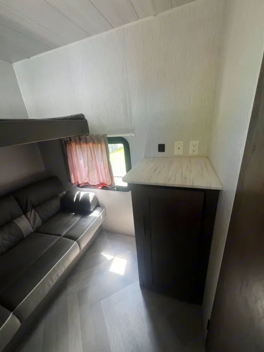 RV rental interior: Bunk bed, sofa, a small counter with outlets, and light wood herringbone flooring.. Forest River Salem Cruise Lite 2022