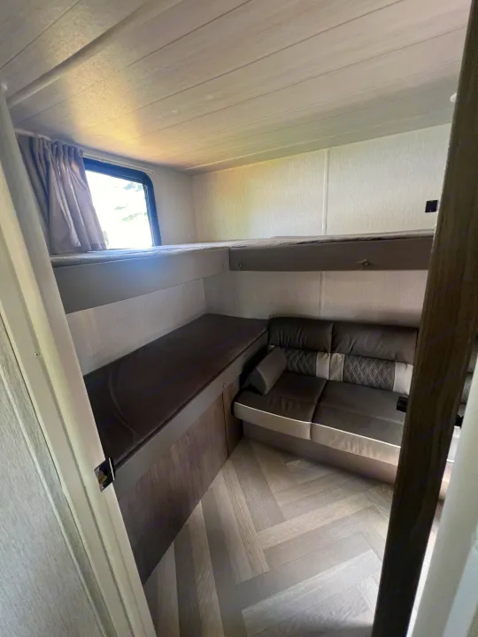 Cozy RV rental interior featuring comfortable bunk beds, a modern sofa, and a bright window.. Forest River Salem Cruise Lite 2022