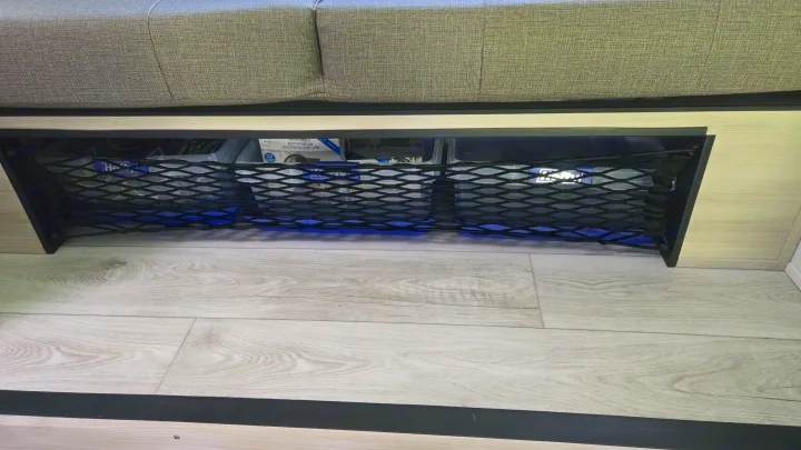 Under-seat mesh storage with blue light in an RV rental. Perfect for keeping travel essentials organized.. East to West Silver Lake 2024