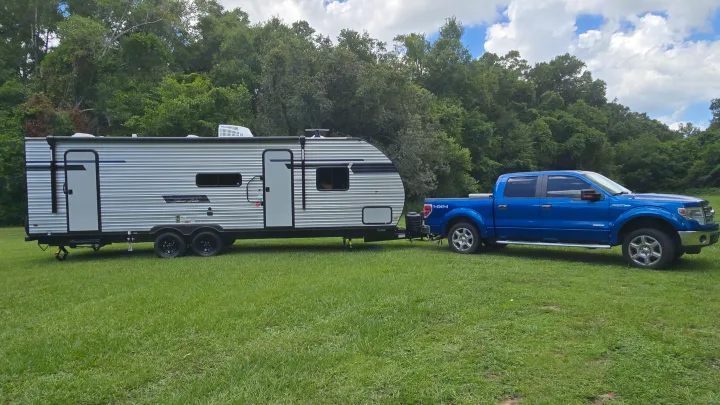 Blue pickup truck and travel trailer, ready for your RV rental camping trip in nature.. East to West Silver Lake 2024
