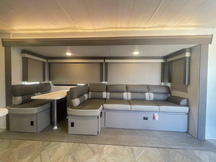 Spacious RV rental interior featuring a modern grey dinette, L-shaped sofa, and under-seat storage.. Forest River Wildwood 2022
