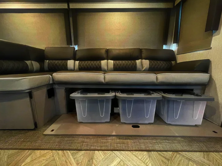 RV rental's L-shaped grey sofa features pull-out under-seat storage bins for organized living space.. Forest River Wildwood 2022