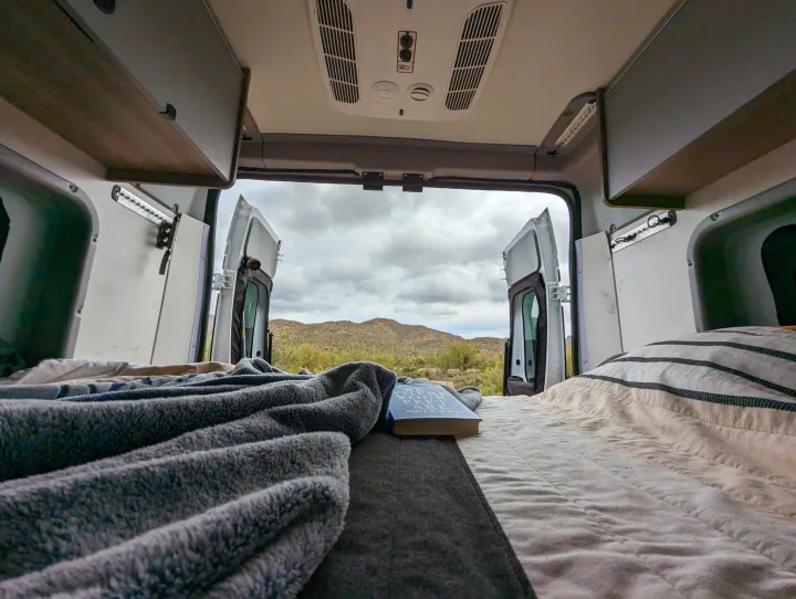 From bed in an RV rental, enjoy desert mountain views. Perfect for a cozy van adventure and exploring nature.. Winnebago Solis 2021