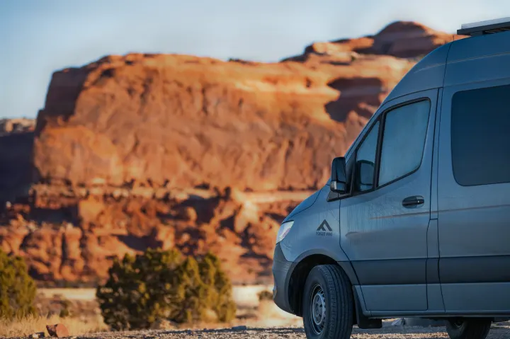 Grey RV rental camper van parked in a stunning red rock desert landscape under a clear blue sky, ideal for outdoor adventures.. Mercedes Sprinter 2500 2020