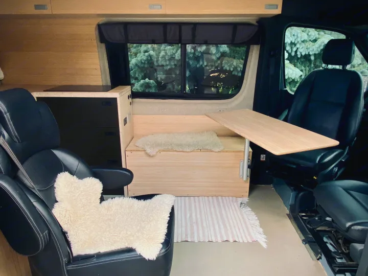 RV rental interior: a compact camper van with wooden walls, bench, table, and kitchen counter.. Mercedes Sprinter 2500 2020