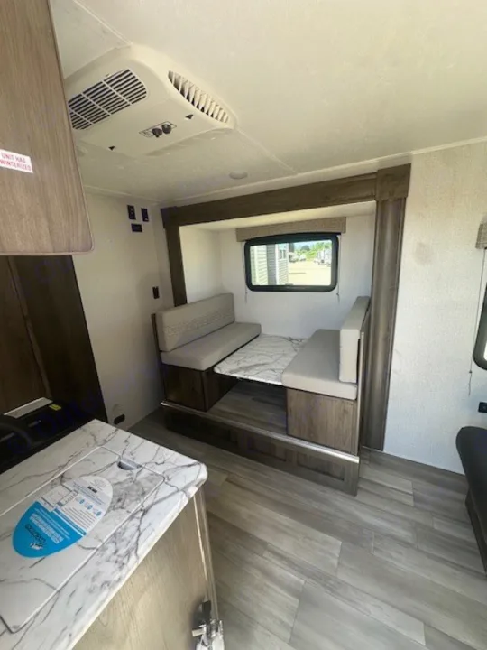 Spacious RV rental interior featuring a cozy dinette, kitchen counter, and ceiling-mounted AC unit. Ideal for camping trips.. Viking SAGA 17FQS 2022