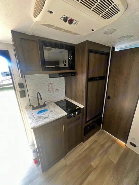 Experience comfort in this RV rental! Features a compact kitchen with microwave, two-burner stove, sink, and fridge.. Viking SAGA 17FQS 2022