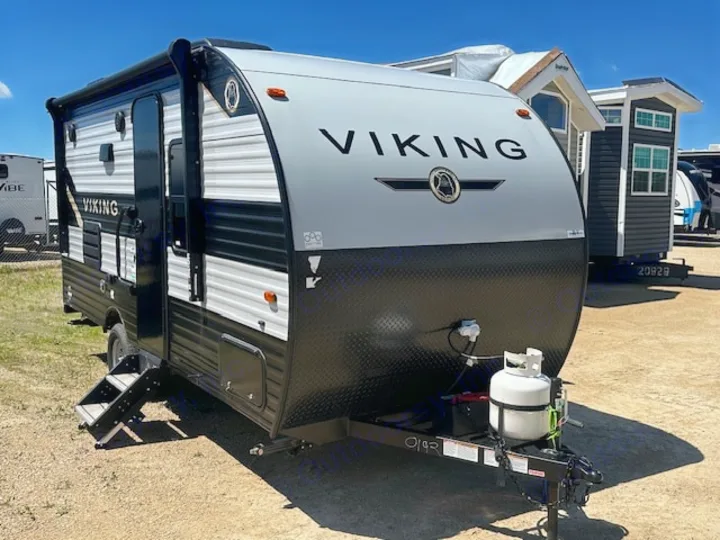 A compact black & gray Viking travel trailer RV rental. Steps lowered, with a visible propane tank and battery on the hitch.. Viking SAGA 17FQS 2022