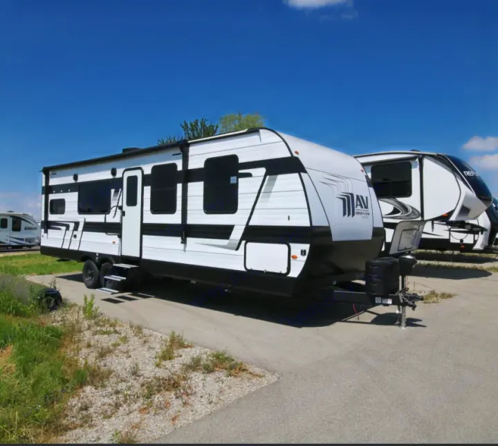 Two travel trailers, a white and black one in front, parked on asphalt under a blue sky. Ideal for an RV rental.. Grand Design Grand Design Trailer 2024