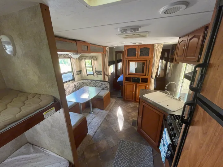 Inside this **rv rental**: a cozy dinette, well-equipped kitchen, entertainment hub, and bunk beds. Ready for your trip.. Keystone RV Passport Ultra 2013