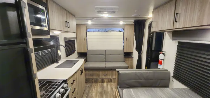 Explore this modern rv rental interior: compact kitchen, cozy living/dining area, and convertible sleeping spaces ready for adventure.. Keystone RV Passport SL 2022