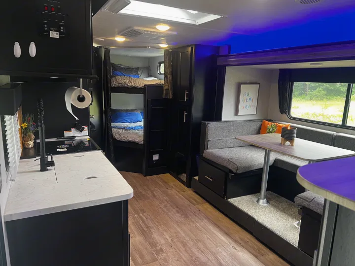 Modern RV rental interior featuring a full kitchen, bunk beds, and a comfortable dinette with outdoor views.. Forest River Cherokee Grey Wolf 2021