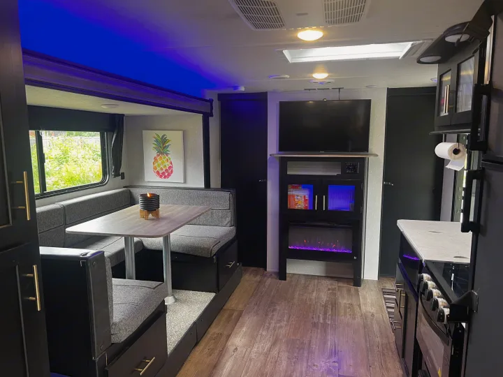 Cozy RV rental interior featuring a modern dinette, entertainment center with fireplace, and full kitchen setup.. Forest River Cherokee Grey Wolf 2021