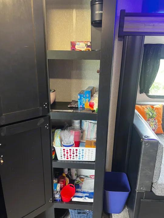 Inside an rv rental: a well-stocked pantry featuring a Keurig, snacks, disposable cups, and grilling supplies.. Forest River Cherokee Grey Wolf 2021