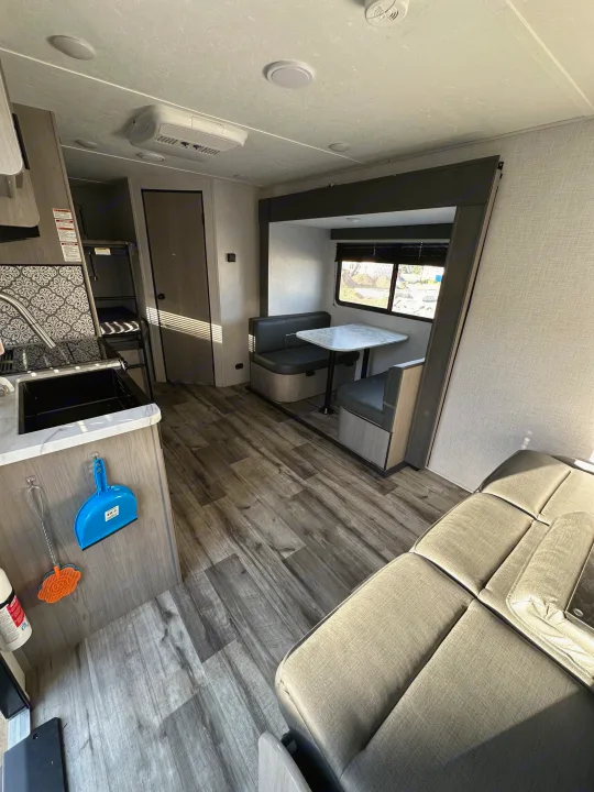Modern RV rental interior showcasing a full kitchen, dinette, cozy sofa, and bunk beds. Ideal for adventure travel.. Dutchmen Coleman Light 2022