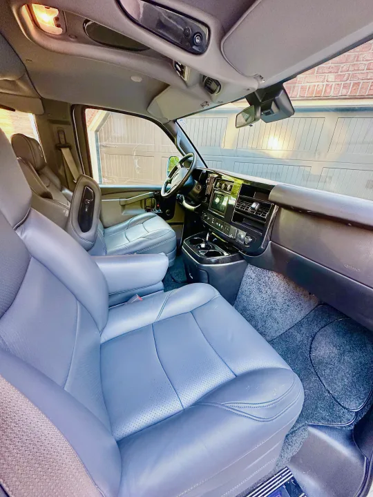 Experience comfort in this RV rental! Interior view of a spacious van, featuring plush gray leather seats, a modern dashboard, and bright cabin lighting.. CHEVROLET Cargo Van 2020