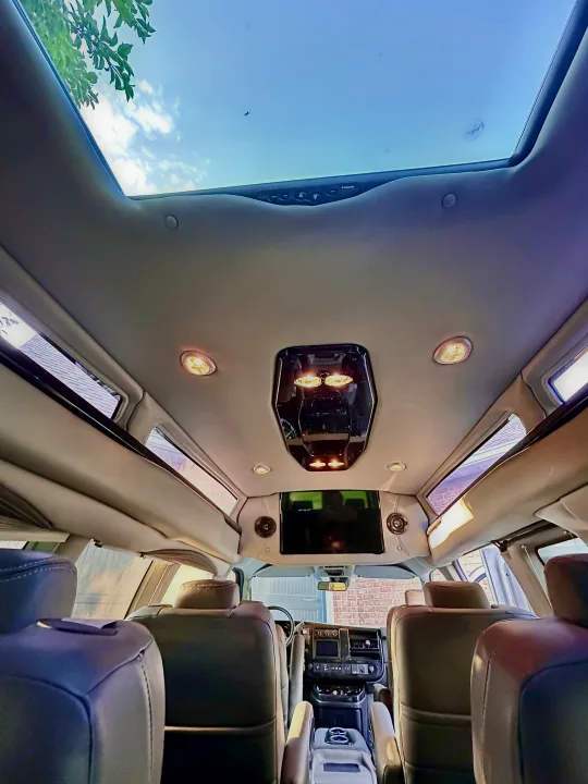 Inside a luxurious RV rental conversion van, featuring plush seats, a large skylight, and a mounted screen.. CHEVROLET Cargo Van 2020