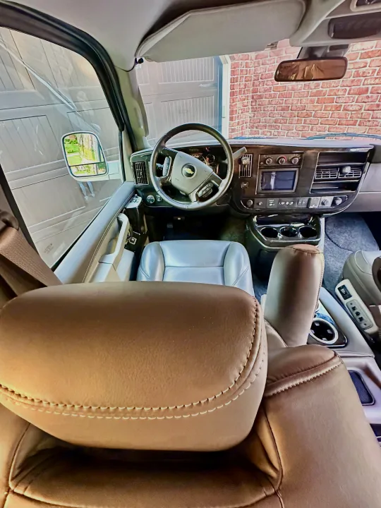 Inside a comfortable RV rental: view from rear passenger seat of the spacious front cabin, dashboard, and steering wheel.. CHEVROLET Cargo Van 2020