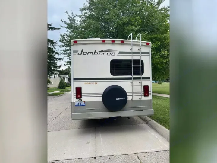 A white Fleetwood Jamboree RV, shown from the rear with a ladder and spare tire, ideal for **rv rental** journeys.. Jamboree Jamboree Motorhome 2004
