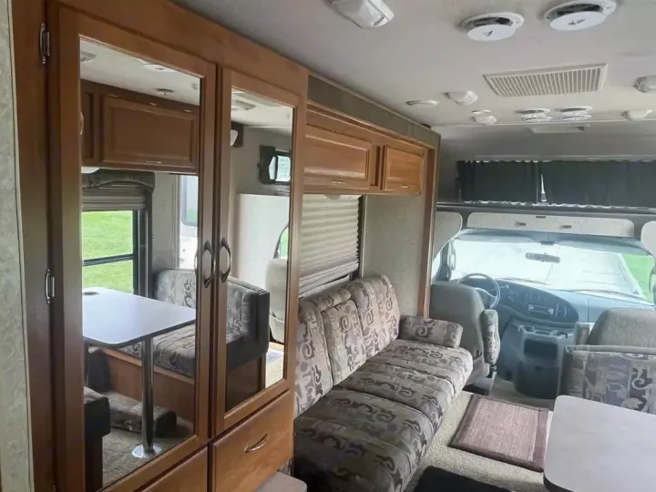 RV rental interior showing a living area with sofa, mirrored closet, dining booth (reflection), and front cabin.. Jamboree Jamboree Motorhome 2004