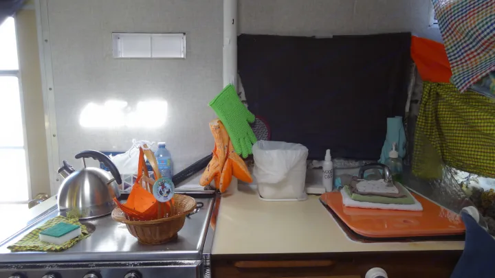 Inside an RV rental: a compact kitchen with a kettle, stove, gloves, and sink for convenient living.. Vintage Trailers Skylark 180 1979
