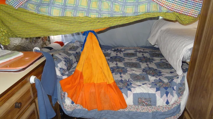 Cozy RV rental interior shows a blanket fort over a patterned bed and a small sink area.. Vintage Trailers Skylark 180 1979