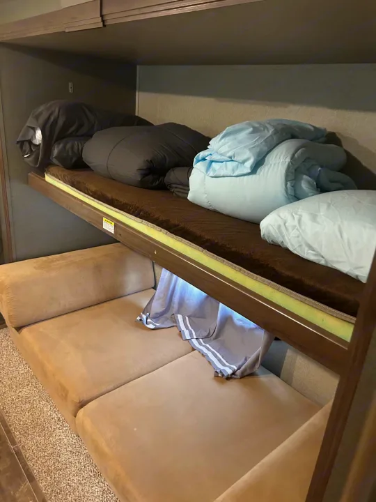 RV rental: Bunk beds with black & blue bedding sit above a tan sofa, offering compact sleeping & living space.. Keystone RV Passport Grand Touring 2018