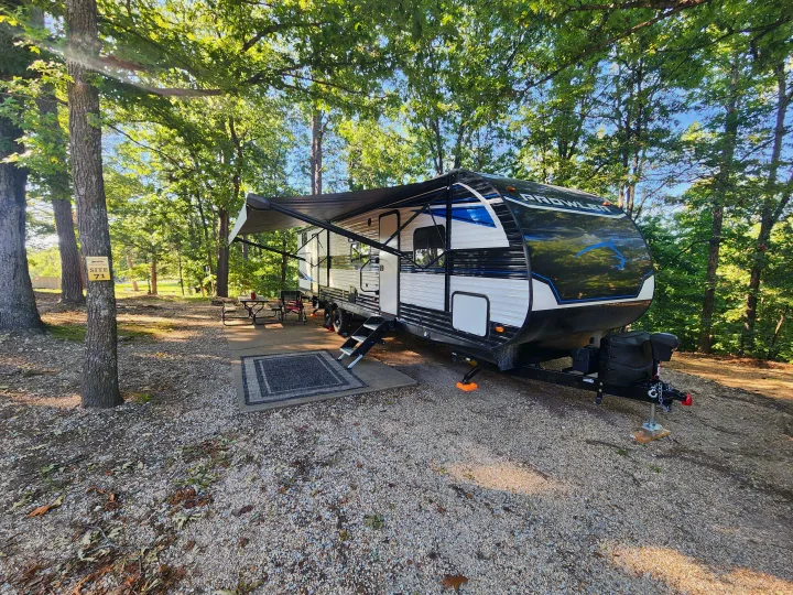 Spacious RV rental campsite (site 71) features a Prowler travel trailer with awning, picnic area, and gravel pad.. Heartland RVs Prowler 2022