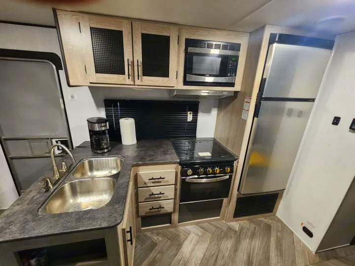 This RV rental features a well-equipped kitchen with a double sink, stove, microwave, refrigerator, and ample storage.. Heartland RVs Prowler 2022