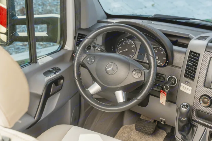 View from an RV rental driver's seat, showing the Mercedes-Benz steering wheel and detailed dashboard controls.. Entegra Coach Qwest 2018