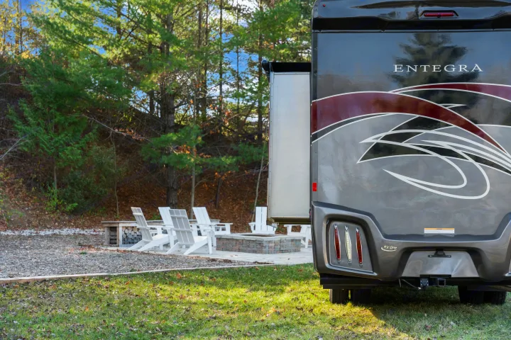 Spacious Entegra RV rental parked at a relaxing campsite with a fire pit and seating area, perfect for outdoor living.. Entegra Coach Qwest 2018