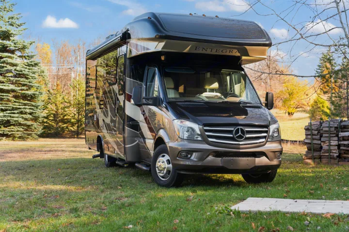 This sleek Entegra motorhome RV rental is ready for adventure, parked in a scenic grassy setting under a blue sky.. Entegra Coach Qwest 2018