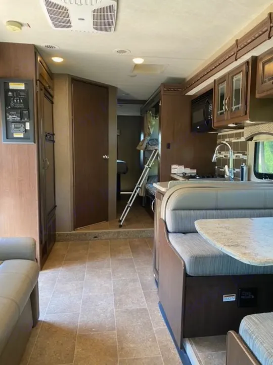 Explore this rv rental's interior: a kitchen, dining booth, & bunk bed area are visible. Features modern wood cabinetry & tiled floor.. Thor Chateau 2017