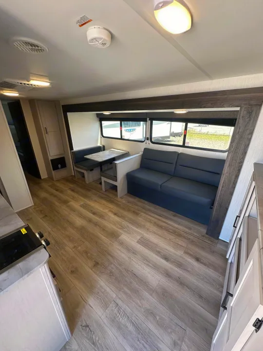 Spacious RV rental interior featuring a dinette, sofa, and kitchen area with wood-look flooring.. Heartland Prowler Lynx 302BHX 2025
