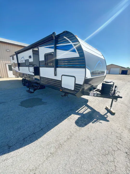 Experience travel with this bright white, black, and blue Lynx travel trailer, ready for your RV rental adventure on a sunny day.. Heartland Prowler Lynx 302BHX 2025