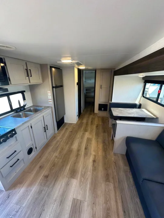 Spacious rv rental interior featuring a modern kitchen, dinette, and living area with wood floors.. Heartland Prowler Lynx 302BHX 2025