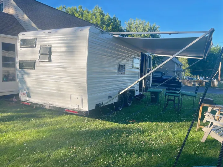 This travel trailer with an extended awning is an ideal RV rental, parked on a green lawn for a getaway.. Sunline T2251 1985