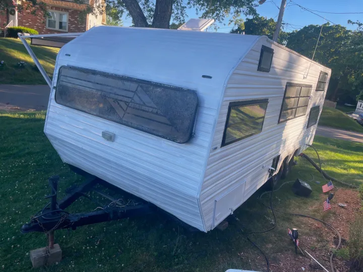 White travel trailer with an extended awning, parked on grass. Great for your next RV rental adventure.. Sunline T2251 1985