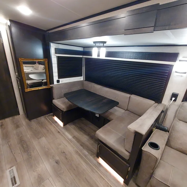 Inside this modern RV rental: a dark U-shaped dinette, comfortable recliners, light wood-look floor, and dark cabinetry.. Jayco White Hawk 2021