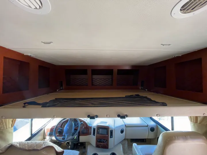 Inside an RV rental: view from the living area towards the cockpit, showcasing the overhead bunk, dashboard, and storage.. Thor Motor Coach A.C.E 2017