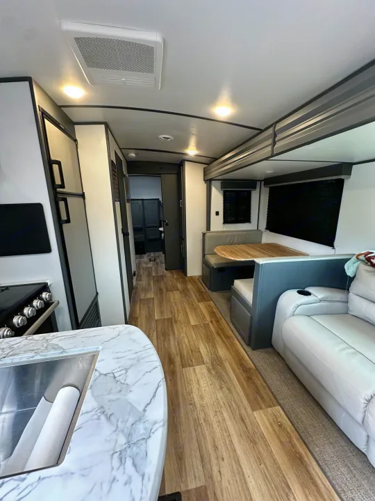 Spacious and modern RV rental interior with a kitchen, dining booth, and comfortable living area featuring a light wood floor.. Keystone RV Bullet Ultra Lite 2022