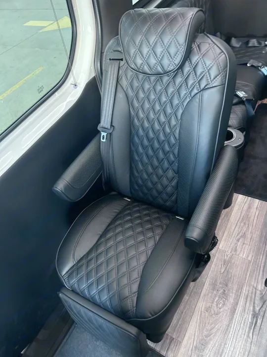 Luxury black leather captain's chair in a premium RV rental interior, featuring diamond stitching and armrests.. Midwest Automotive Designs Luxe Cruiser 2024