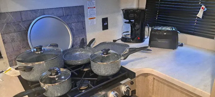 This RV rental kitchen is packed with cooking essentials: various pots, pans, a coffee maker, and toaster, making meal prep easy.. Forest River Aurora Aurora 2024