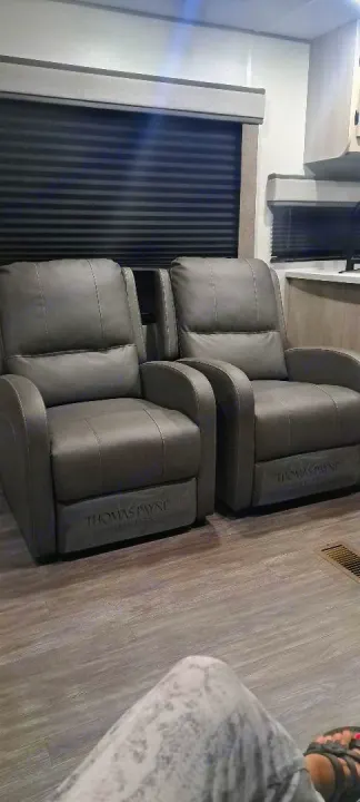 Enjoy comfort in this modern RV rental interior featuring two grey Thomas Payne recliners, wood-look floors, and window shades.. Forest River Aurora Aurora 2024