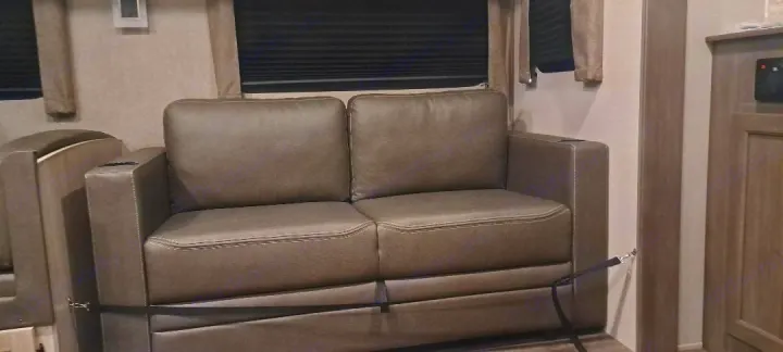 Gray sofa in RV rental living space with cup holders for comfort on the go.. Forest River Aurora Aurora 2024