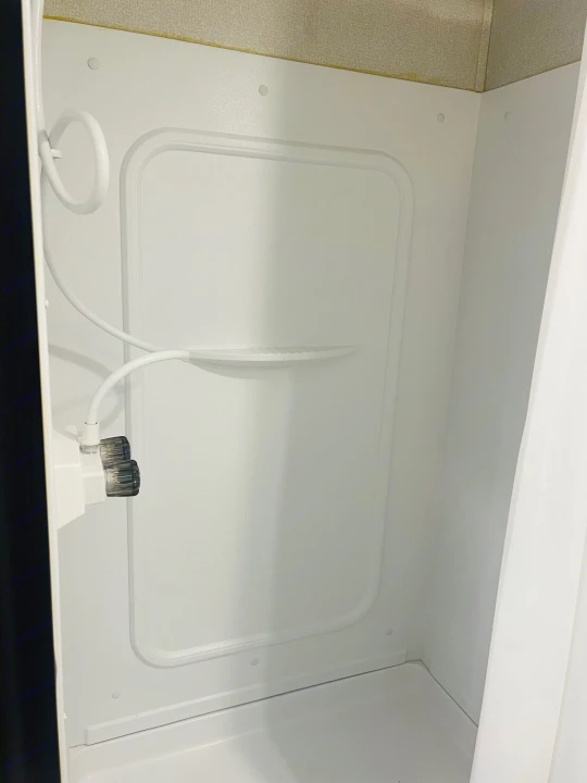 Clean, white RV rental shower with handheld head and built-in shelf. Ideal for a compact travel bathroom experience.. Keystone RV Hideout 2022