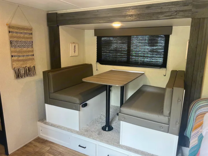 Inside your RV rental: Enjoy meals at this cozy dinette featuring padded benches, a table, and convenient storage.. Keystone RV Hideout 2022